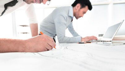 Architectural design process with architects drafting plans at a drafting table